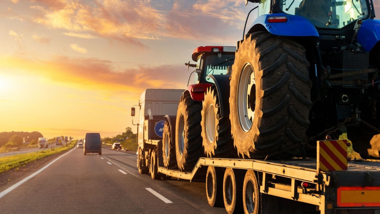 a large truck trailer hauling large-tire tractors down a highway