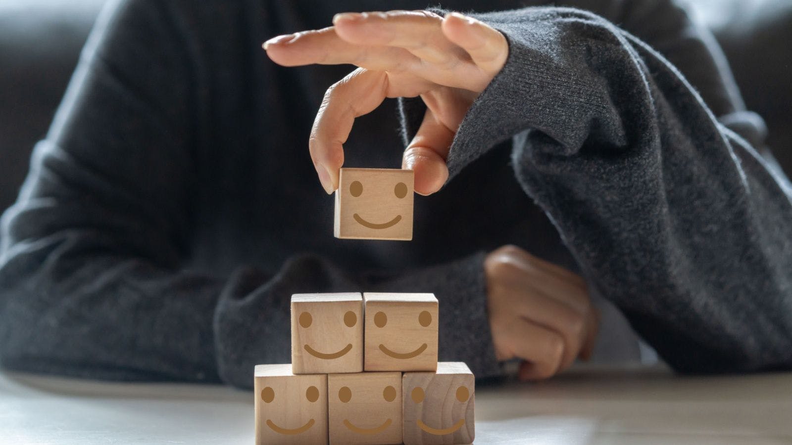 a stack of blocks with smiley faces indicating wellbeing