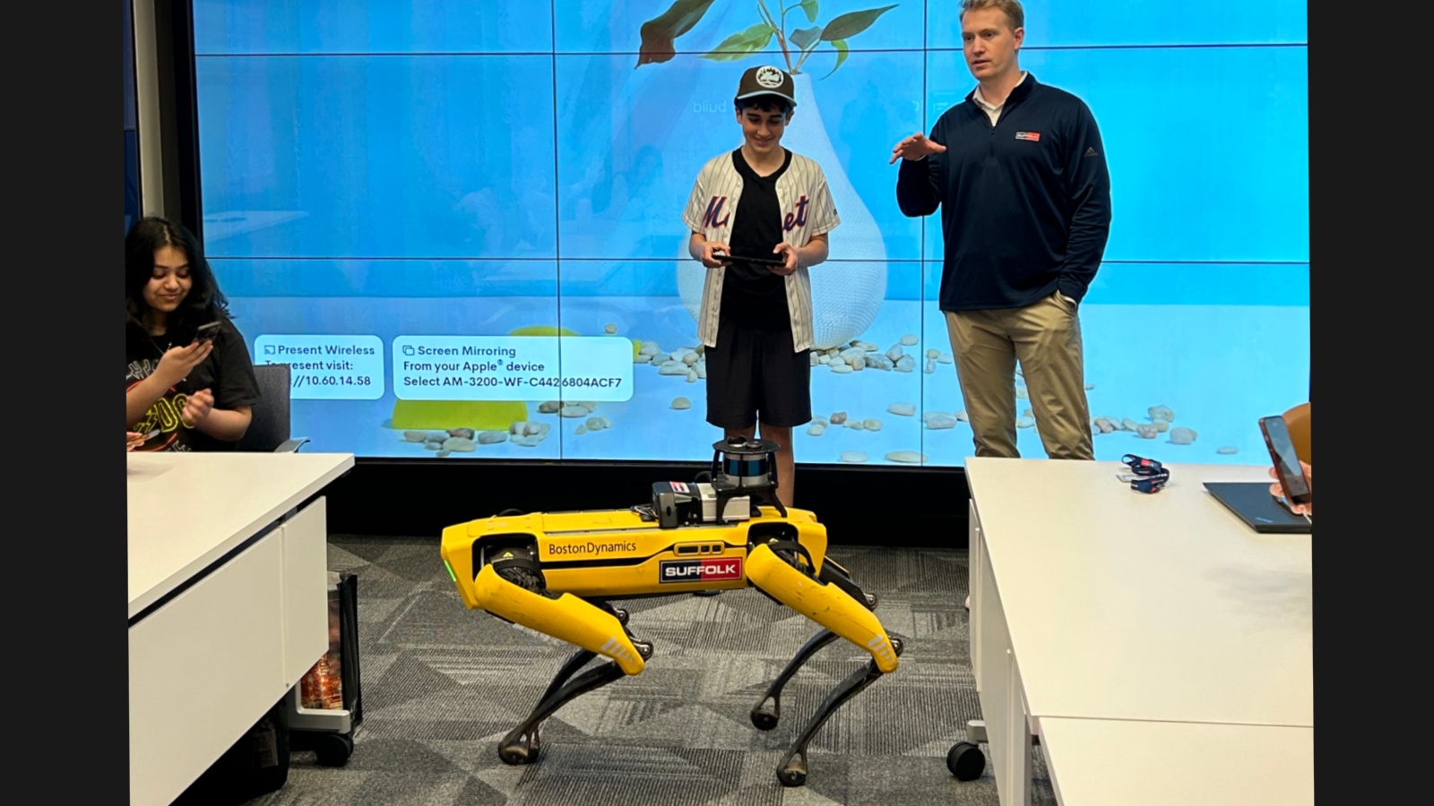 a student involved with the ACE Mentor program learning how to operate Spot the Robot Dog at Suffolk's New York office