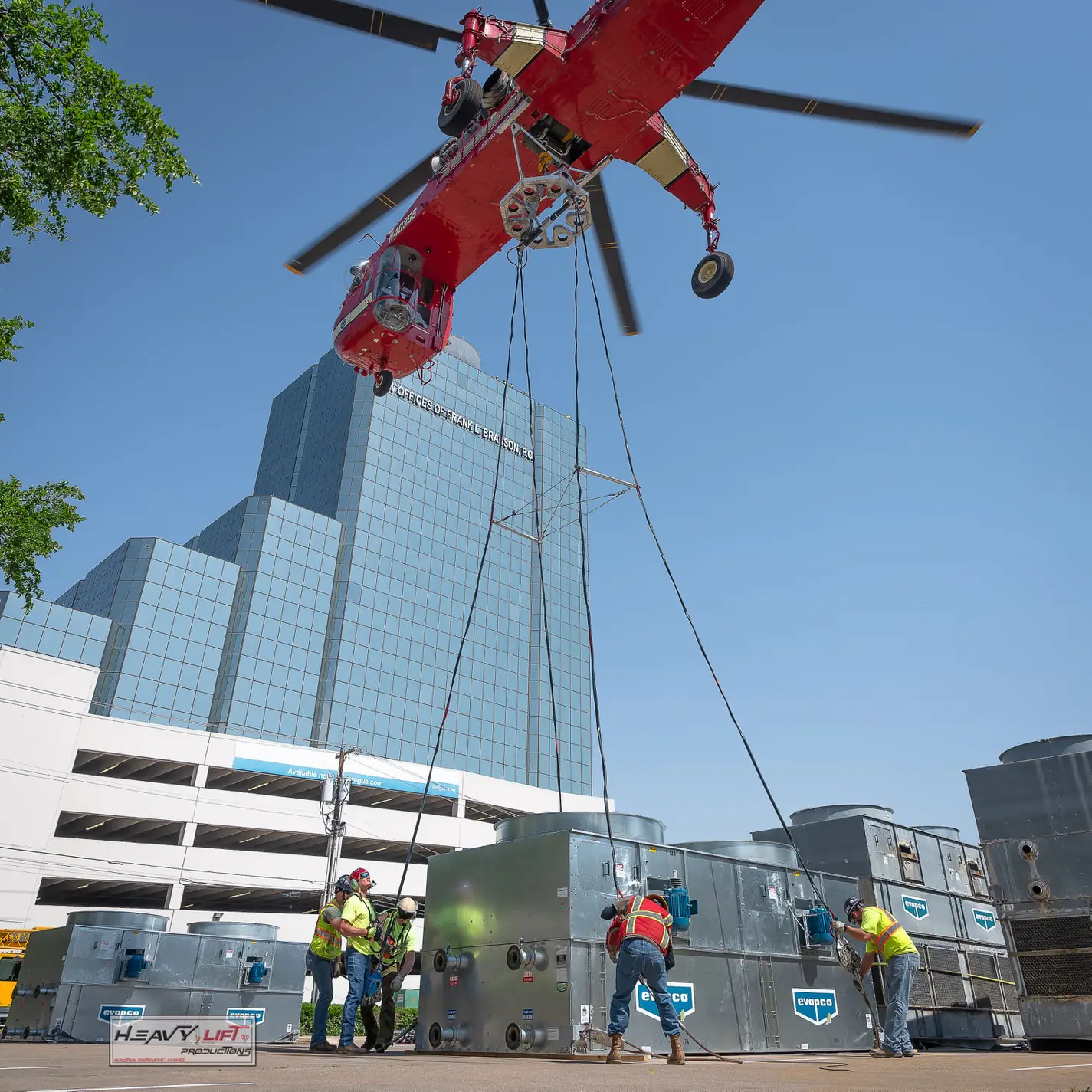 A construction crew rigs up a helicopter from outside of a building to do a complete air cooler system.