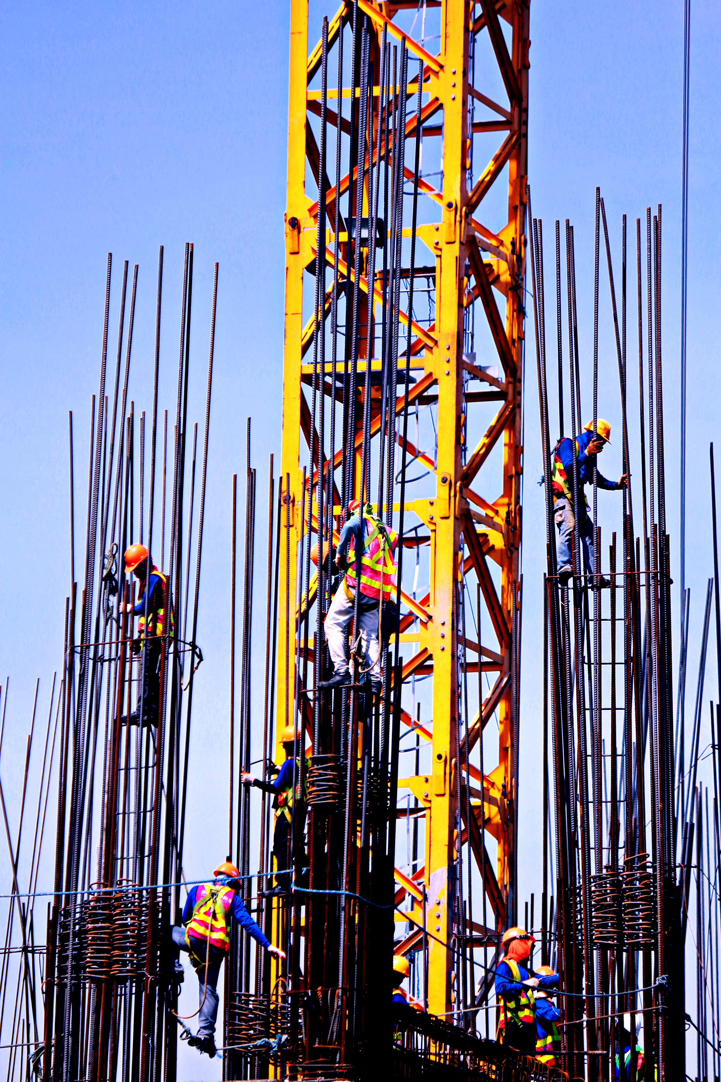 Filipino construction workers assembling pillars on top of a Manila City condominium building.